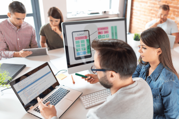 People sitting at a table, looking at computers.