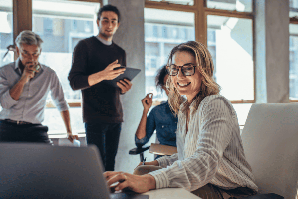 A team of business professionals in an office, looking at a laptop.